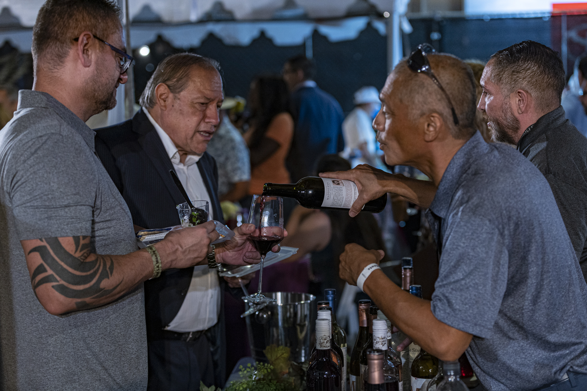 man pouring wine for two men